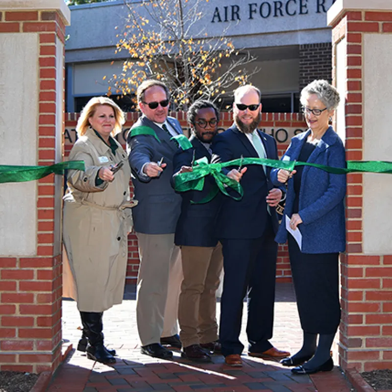 Group of five staff and students cutting a grand-opening ribbon